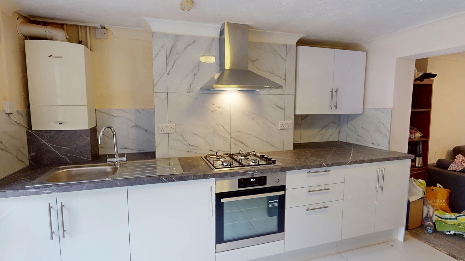 White gloss kitchen fitting with marble-effect splashback and integrated oven, Aberdeen Road Brighton