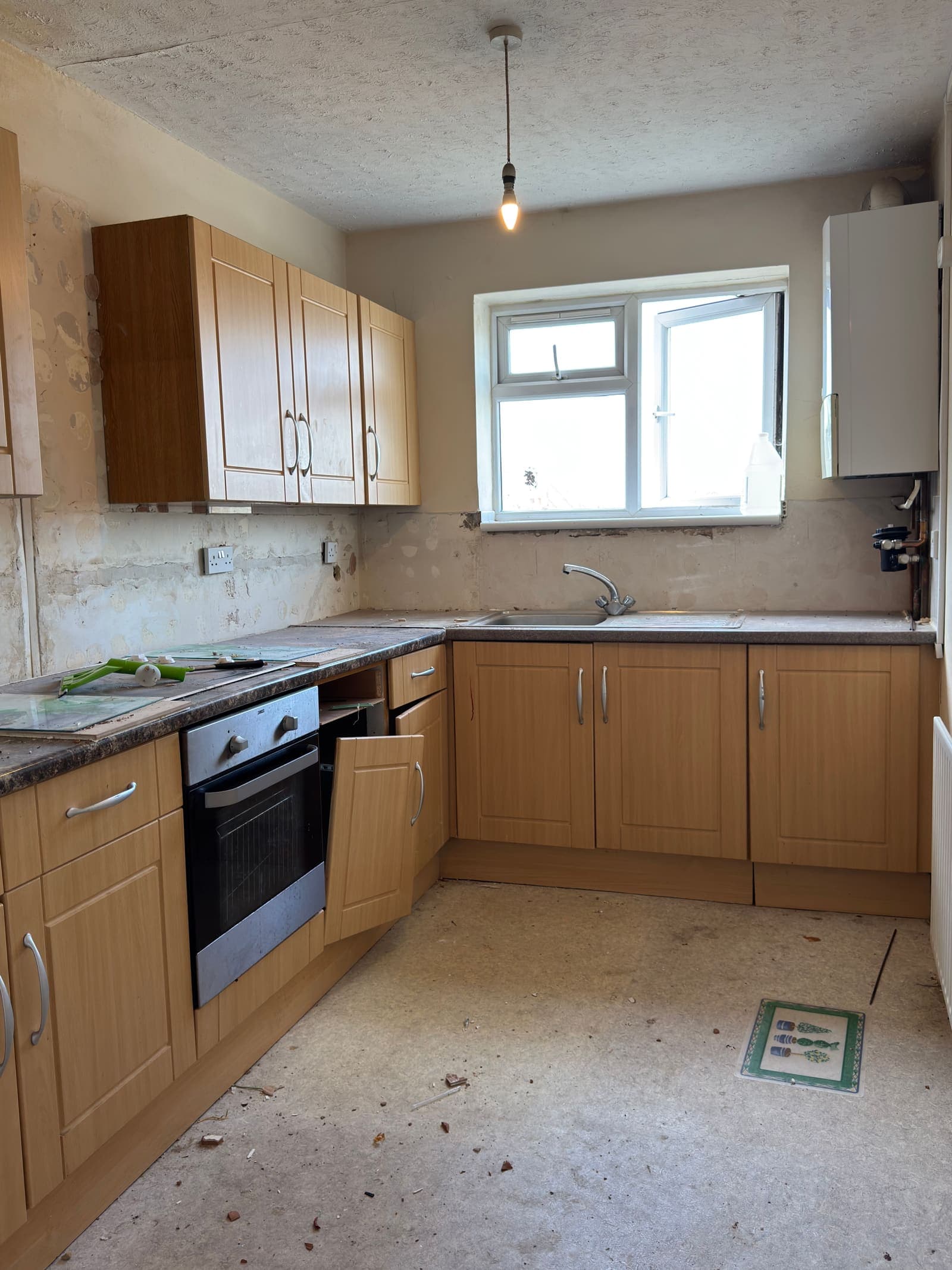 Dated wood-veneer kitchen with worn worktops before refurbishment, Derby Court