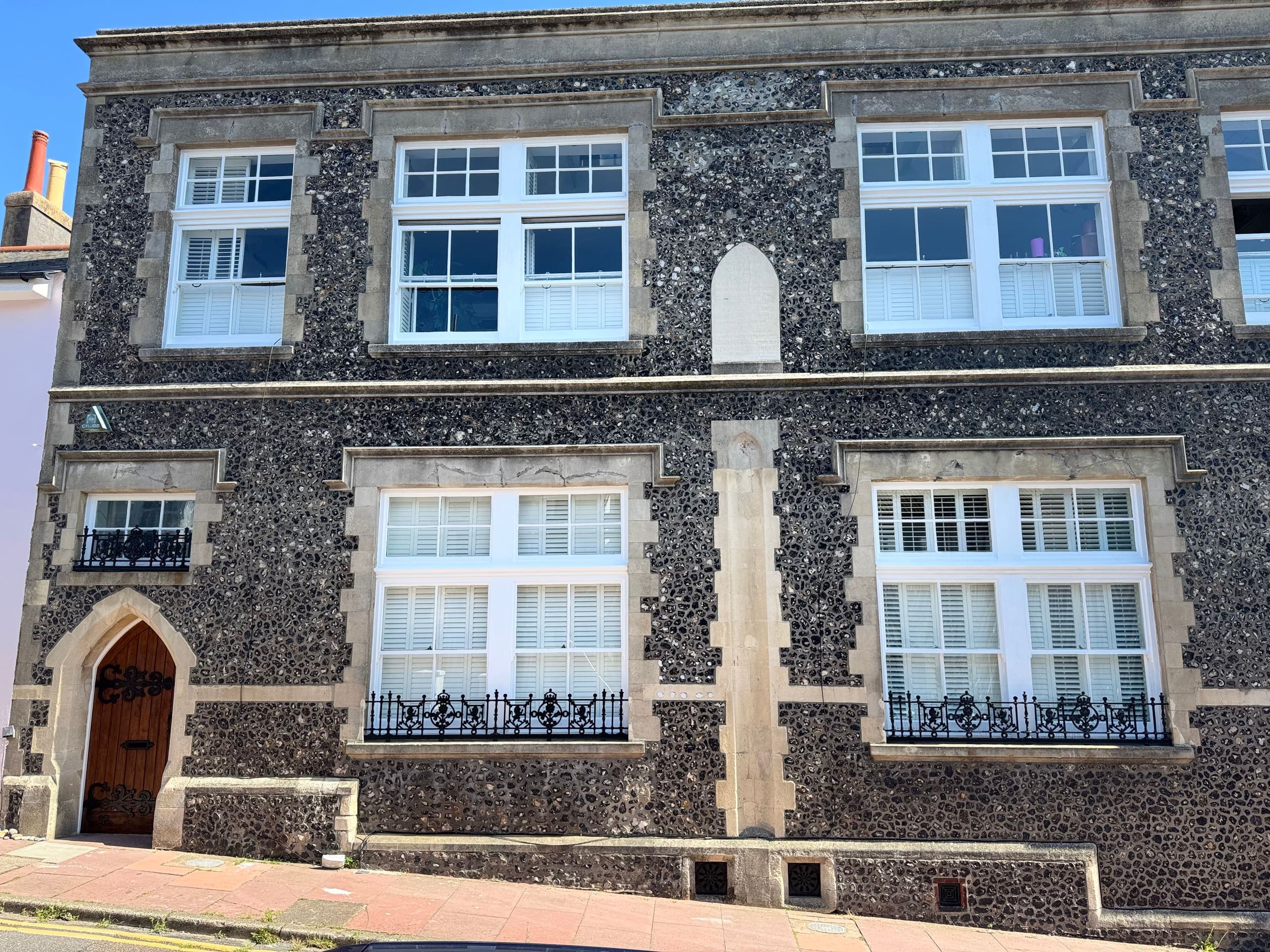 Restored flint period building frontage with repointed stonework and new white windows in Brighton