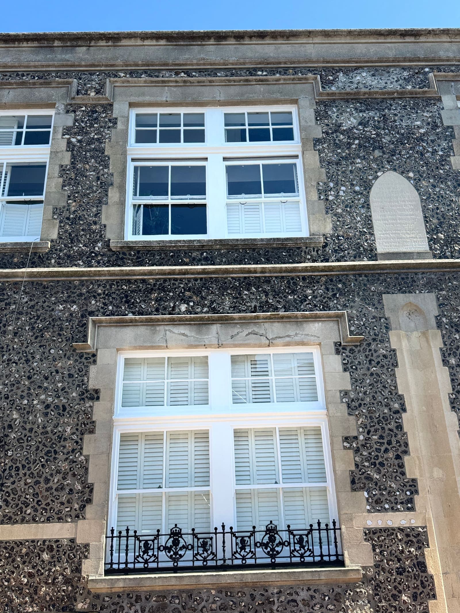 Restored window with fresh white paintwork set in knapped flint stonework, Brighton