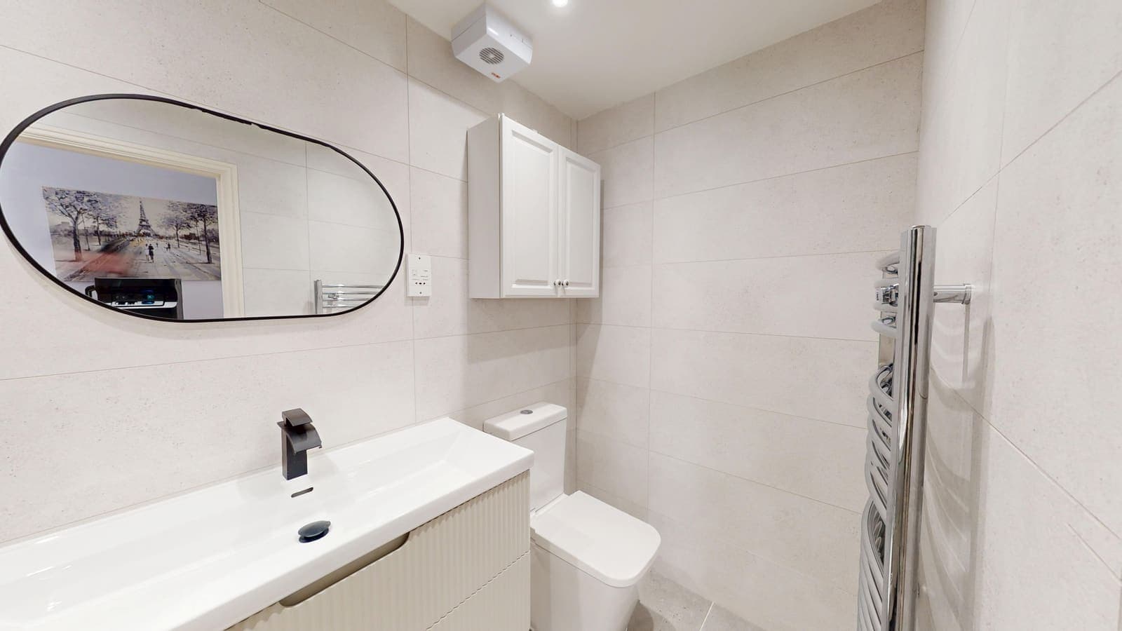 Modern bathroom fitting with wall-hung basin, chrome towel radiator and oval mirror, Holland Road Hove