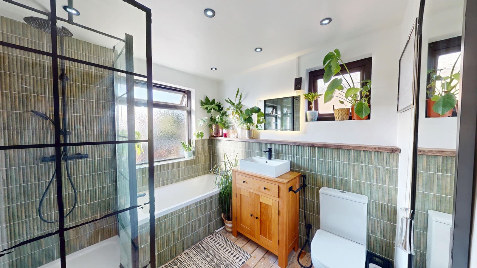 Crittall-style walk-in shower with patterned green wall tiles fitted by Essence Construction
