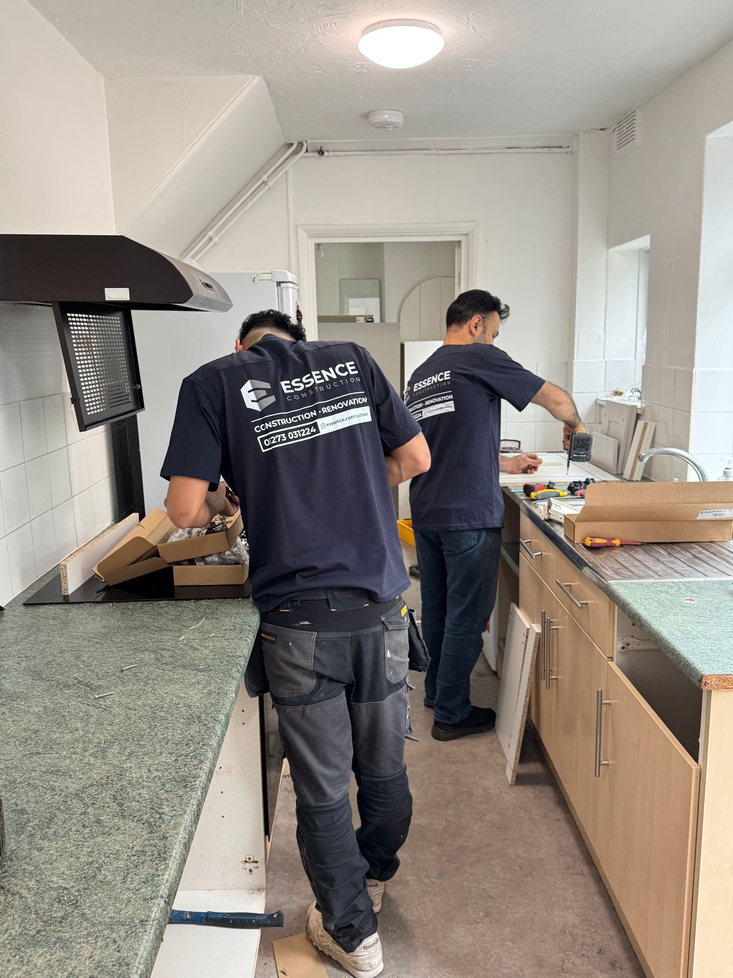 Two Essence Construction fitters in branded workwear installing a kitchen on a Brighton renovation