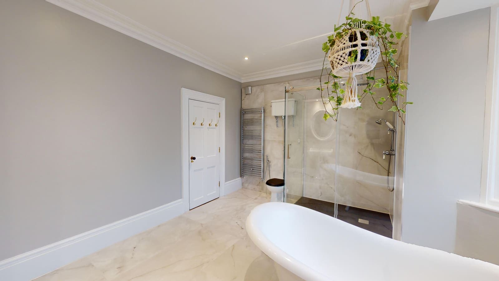 Freestanding roll-top bath against marble-effect walls in a Brighton bathroom renovation
